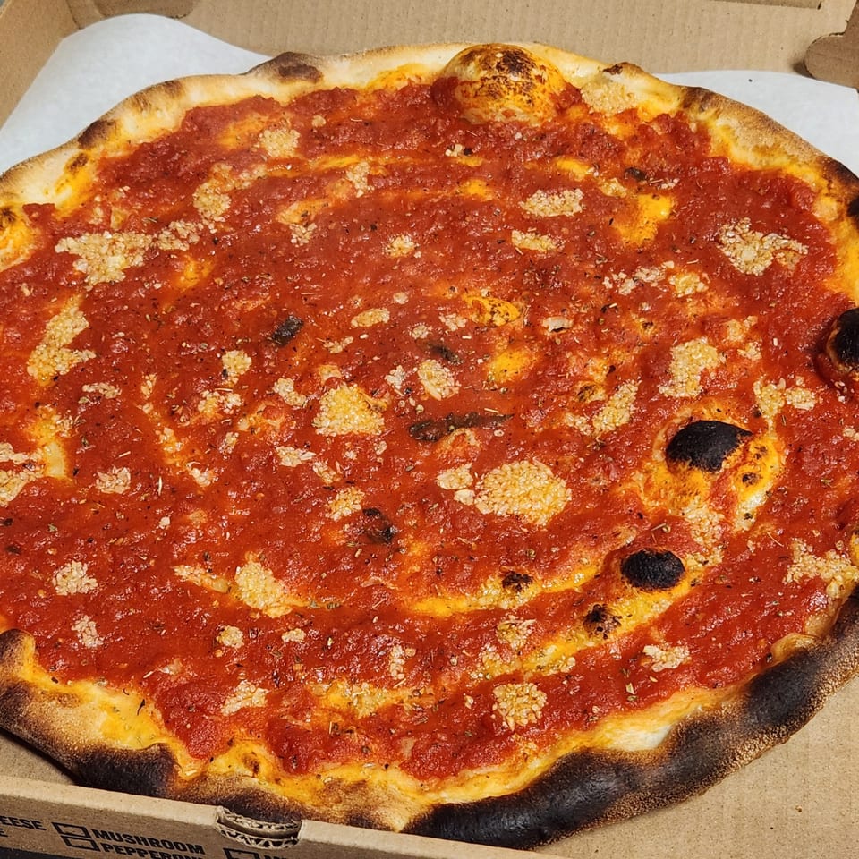 Nostra Pizza Voorhees' tomato pie with a vibrant red sauce and golden-brown crust in a pizza box.