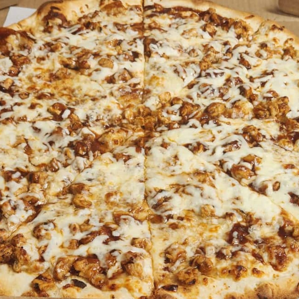 A whole Nostra Pizza Voorhees BBQ chicken pizza, cut into eight slices, with melted cheese and chicken pieces.
